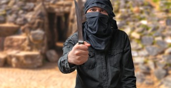 Terrorism concept. Terrorist threatening with knife in desert.