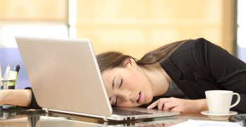 Overworked and tired businesswoman sleeping over a laptop in a desk at work in her office