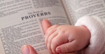Baby Holding Dad's Finger On Bible