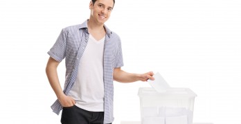 Male voter casting a vote into a ballot box isolated on white ba