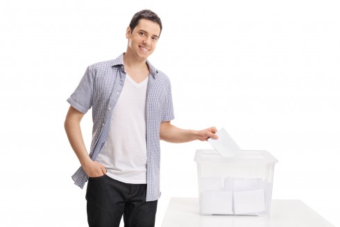 Male voter casting a vote into a ballot box isolated on white ba