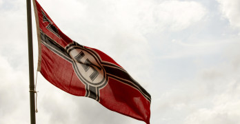 Nazi Germany flag blowing in breeze on flagpole.