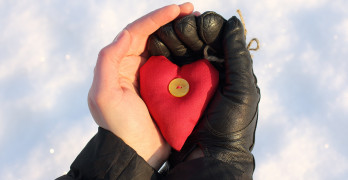 heart symbol in hands of one of them in a black glove
