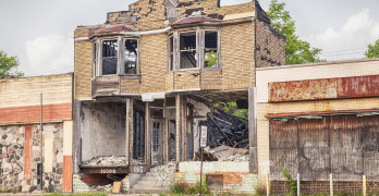 DETROIT USA - JUNE 9 2015: A burned out and semi-demolished building between two closed storefronts on Hamilton Avenue in Detroit Michigan is symbolic of the urban blight that is emblematic of the city.